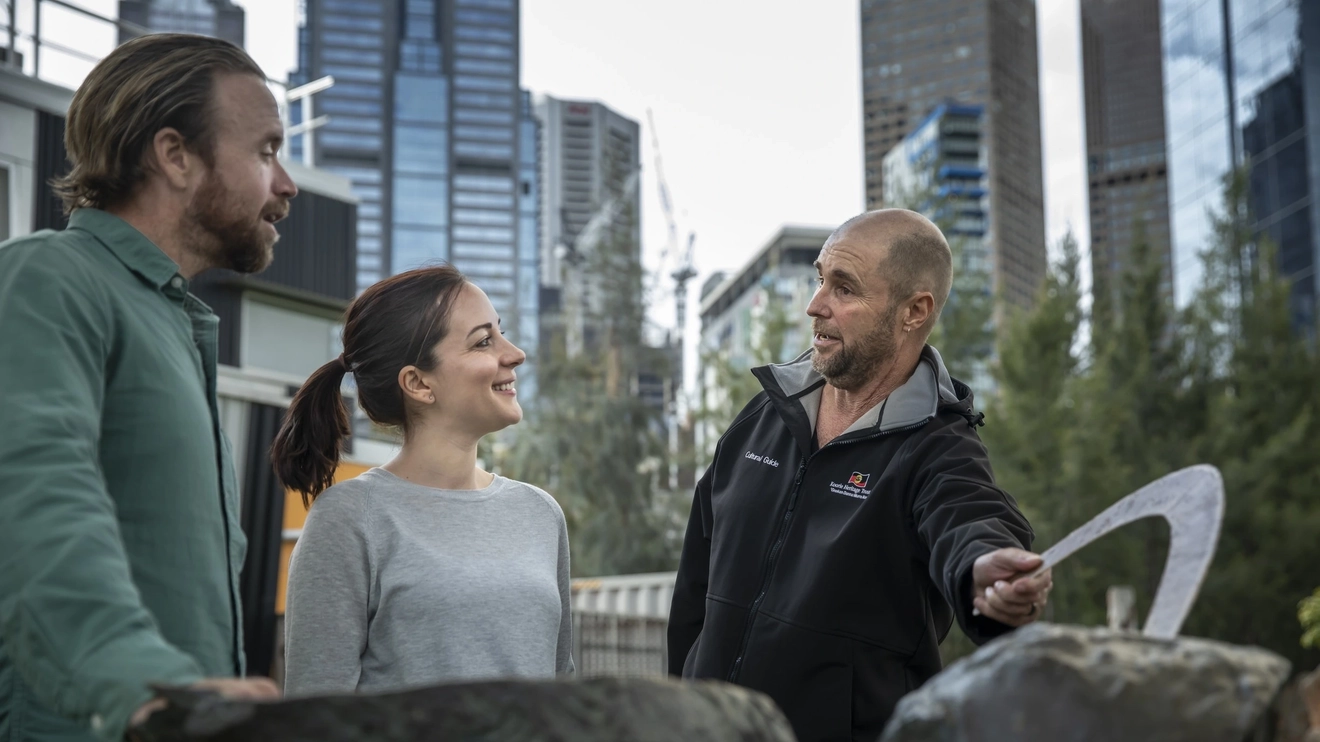 Aboriginal guide talks to tourist couple about boomerang sculpture, Koorie Heritage Trust, Melbourne.