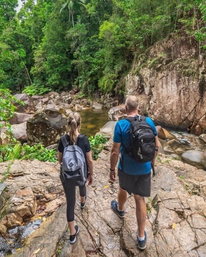 Two people hiking among boulders, rockpools and sub-tropical rainforest at Finch Hatton Gorge, Mackay area. Image credit: Tourism and Events Queensland