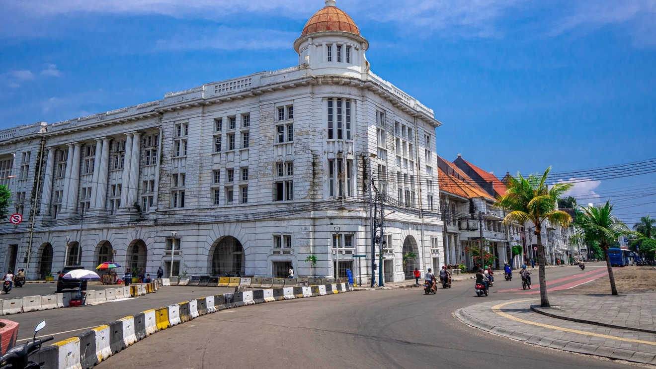 White colonial-era buildings on palm-lined street in Kota Tua, Jakarta’s old town. Image credit: stock.adobe.com