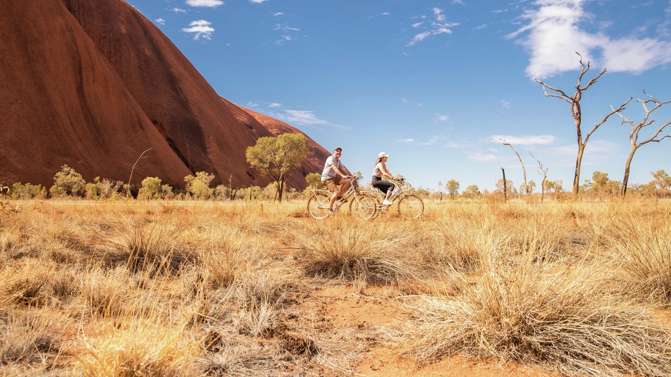 Couple on a bike ride around the base of Uluru, Northern Territory. Image credit: Tourism NT/KWP!