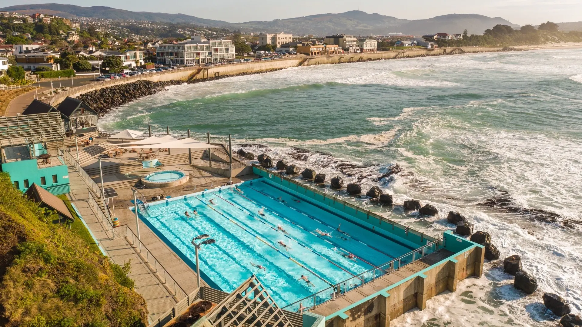 St Clair Beach with outdoor heated pool in the foreground, Dunedin, New Zealand. Image credit: Dunedin NZ