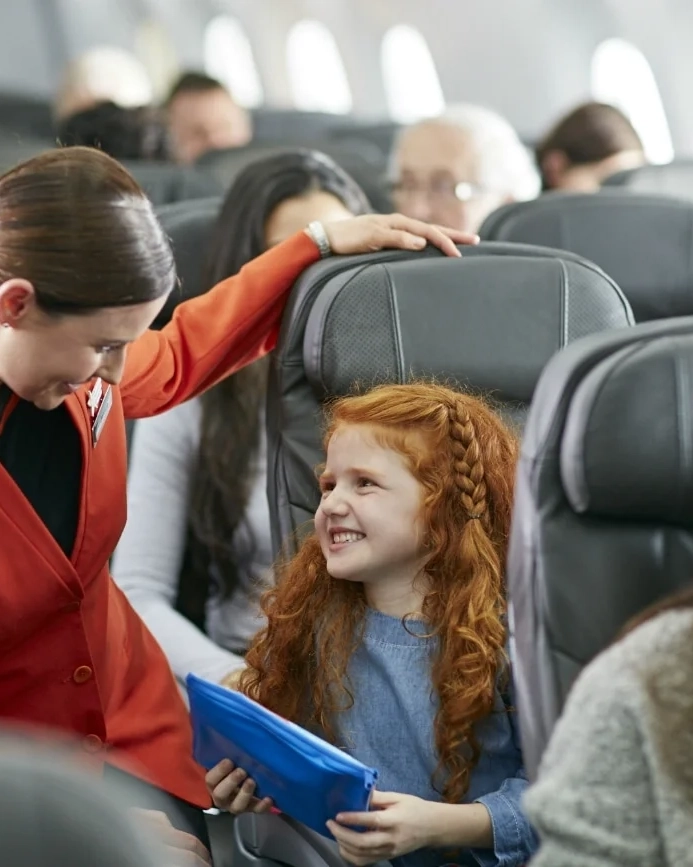 Flight attendant serving the happy young girl.