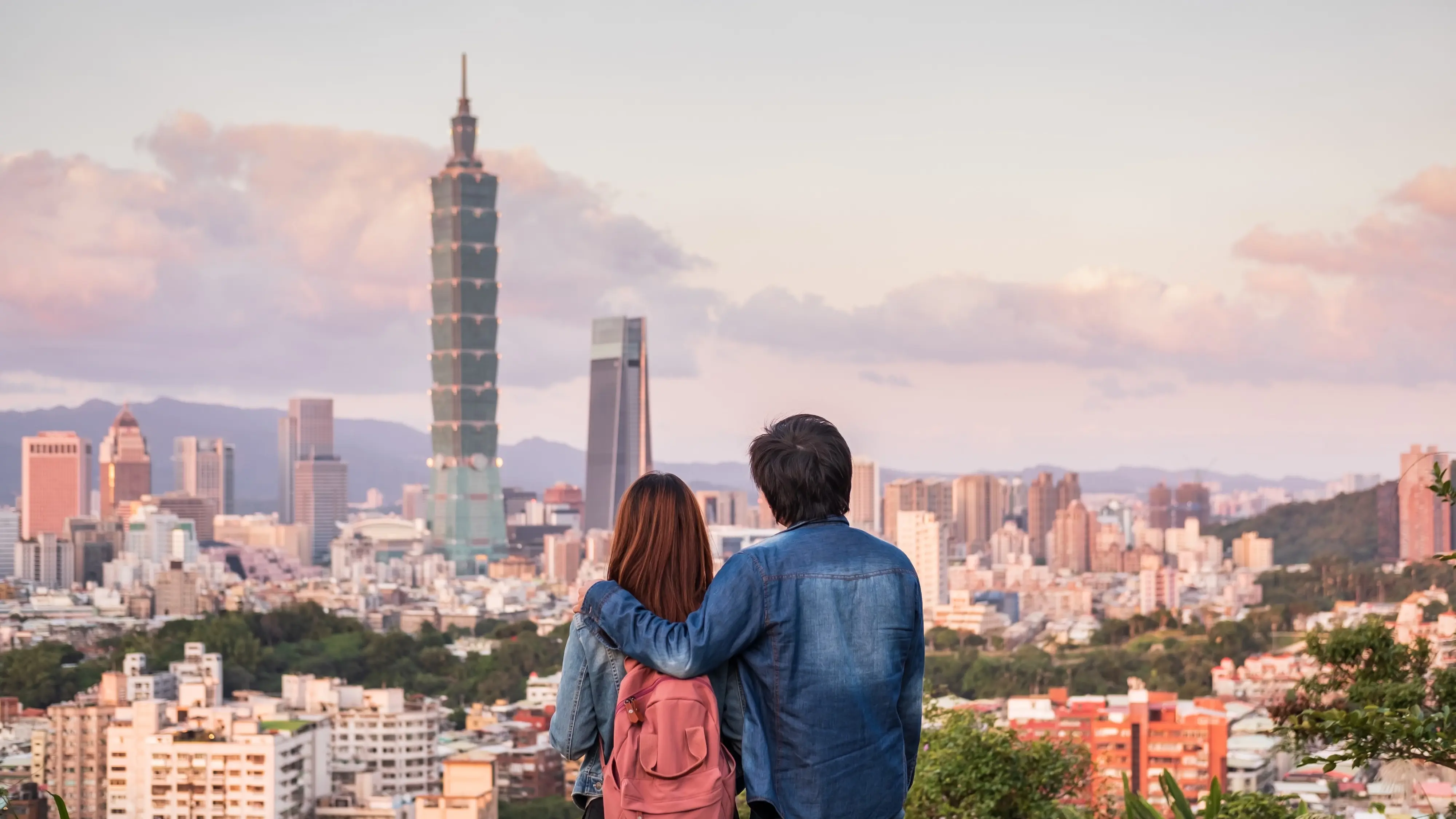 Rear view of couple viewing Taipei city skyline at sunset. Image credit: stock.adobe.com