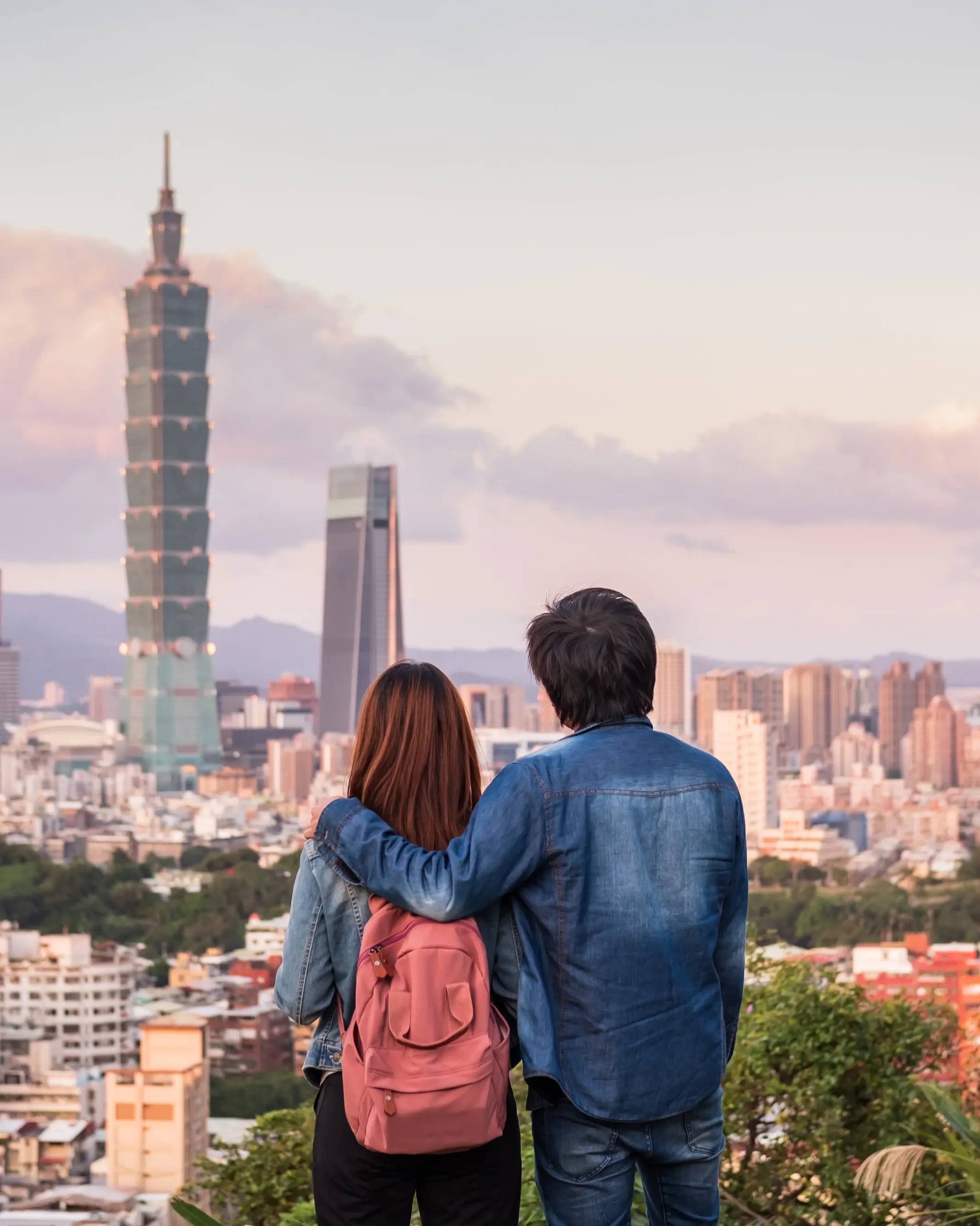 Rear view of couple viewing Taipei city skyline at sunset. Image credit: stock.adobe.com