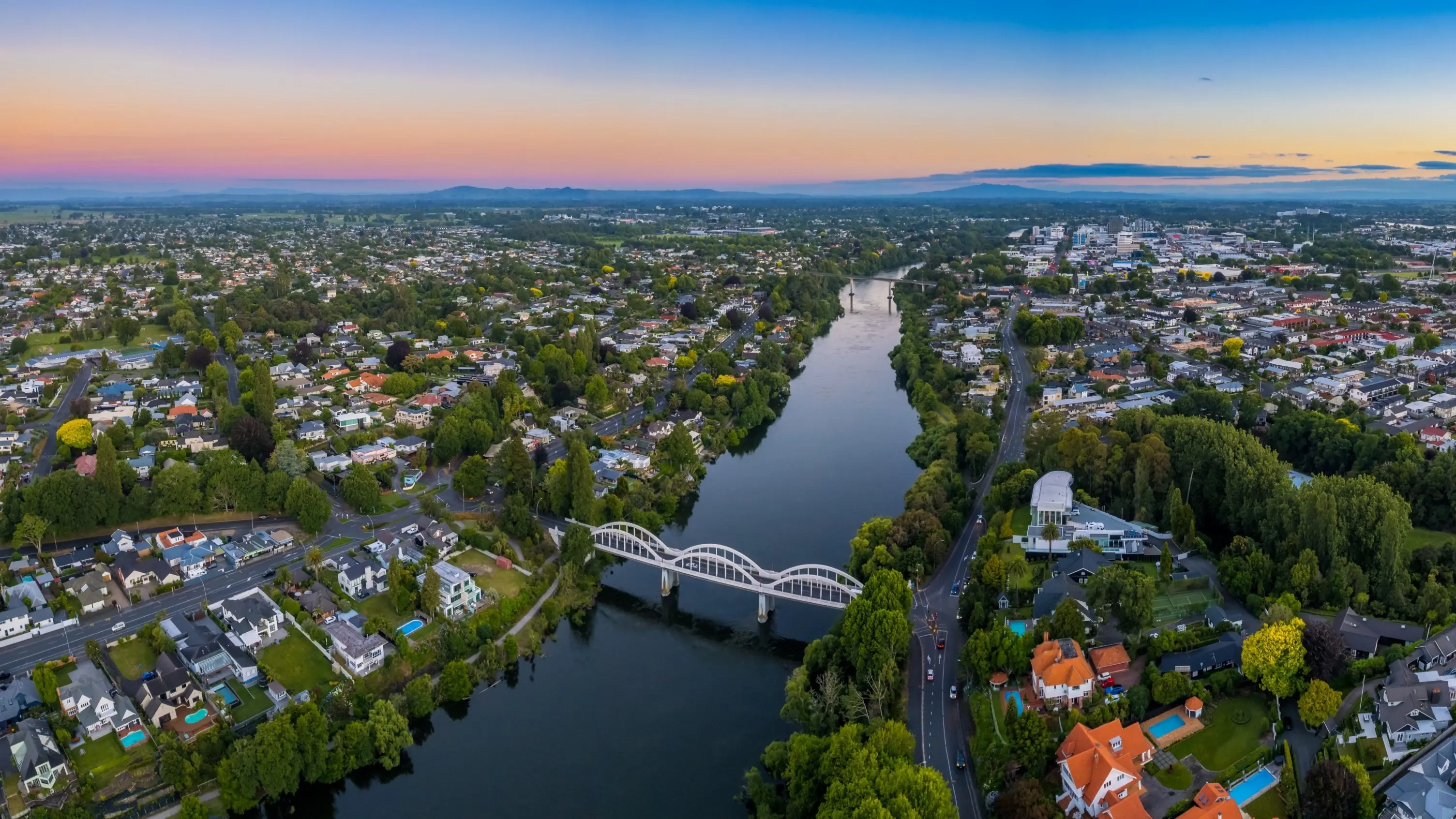 Drone aerial panoramic view of Hamilton, looking up the Waikato River towards the CBD, at sunset. Image credit: stock.adobe.com