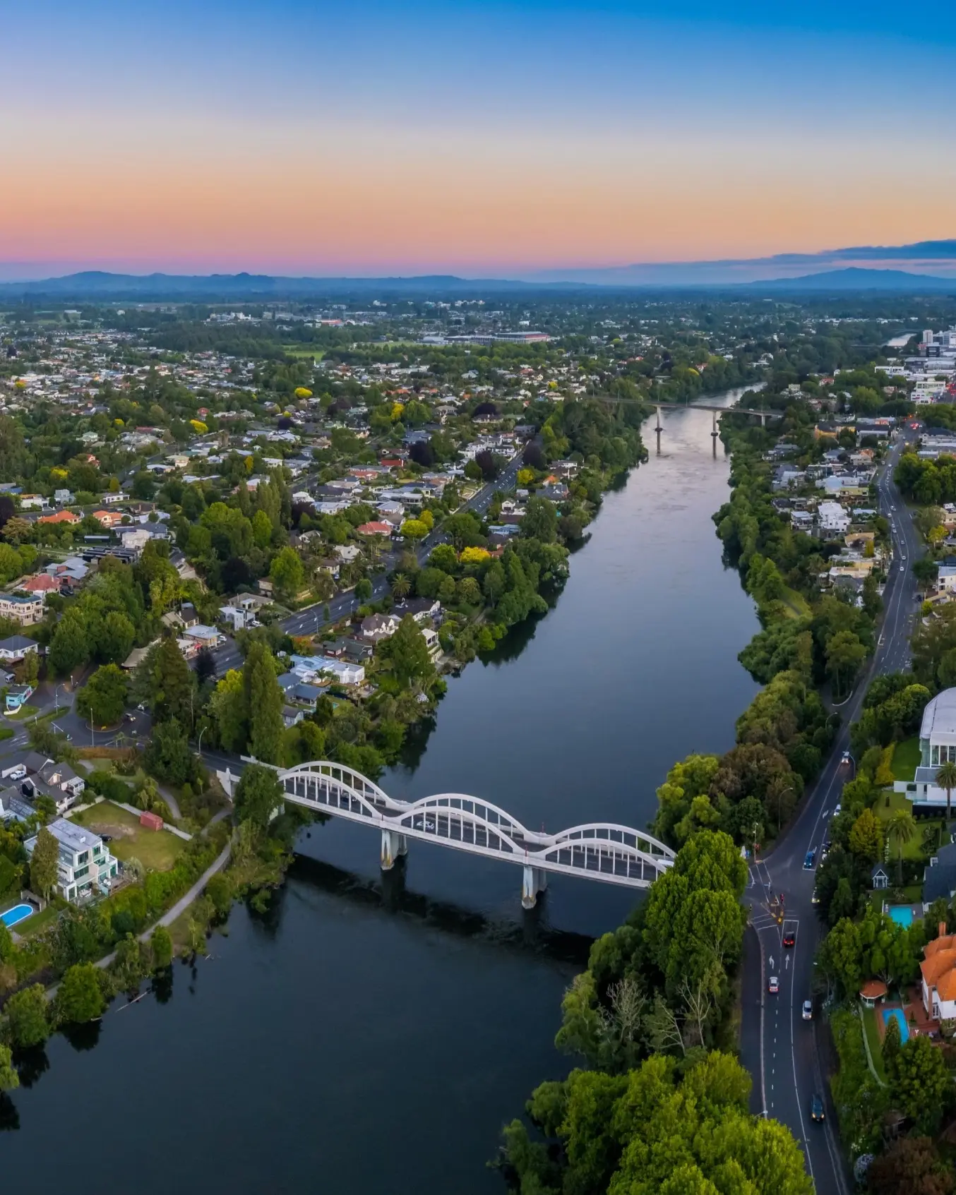 Drone aerial panoramic view of Hamilton, looking up the Waikato River towards the CBD, at sunset. Image credit: stock.adobe.com