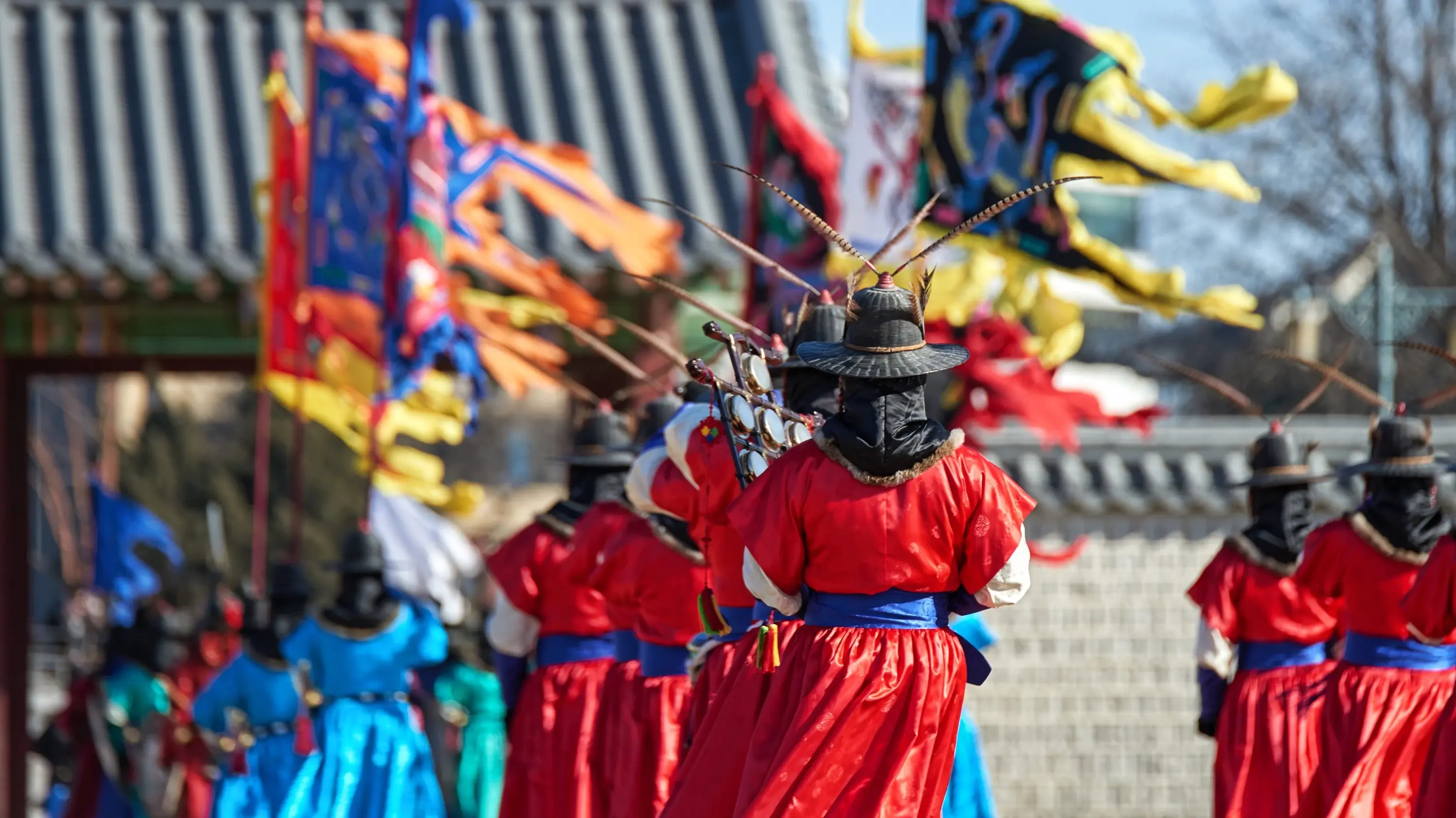 Changing of the Gyeongbokgung Palace guards ceremony showing the back of colourfully dressed guards holding flags in Seoul South Korea. Image credit: stock.adobe.com