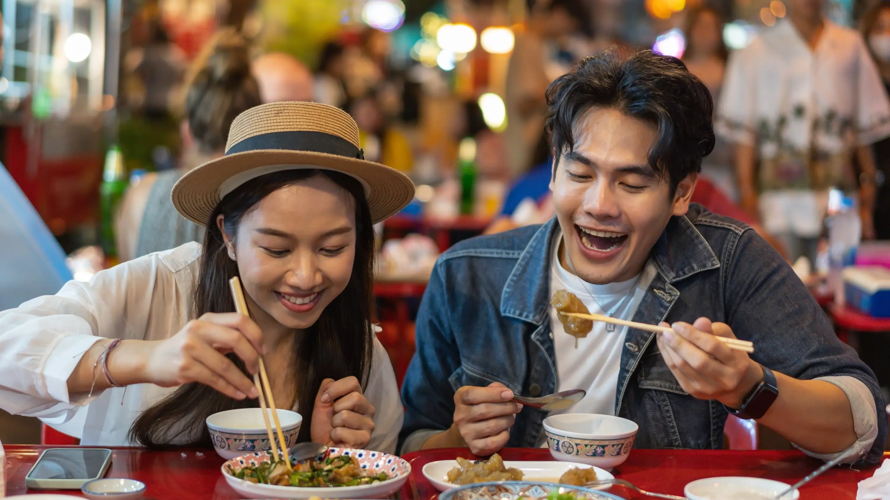 Young Asian couple enjoy Thai street food in Bangkok's bustling Chinatown. Image credit: stock.adobe.com