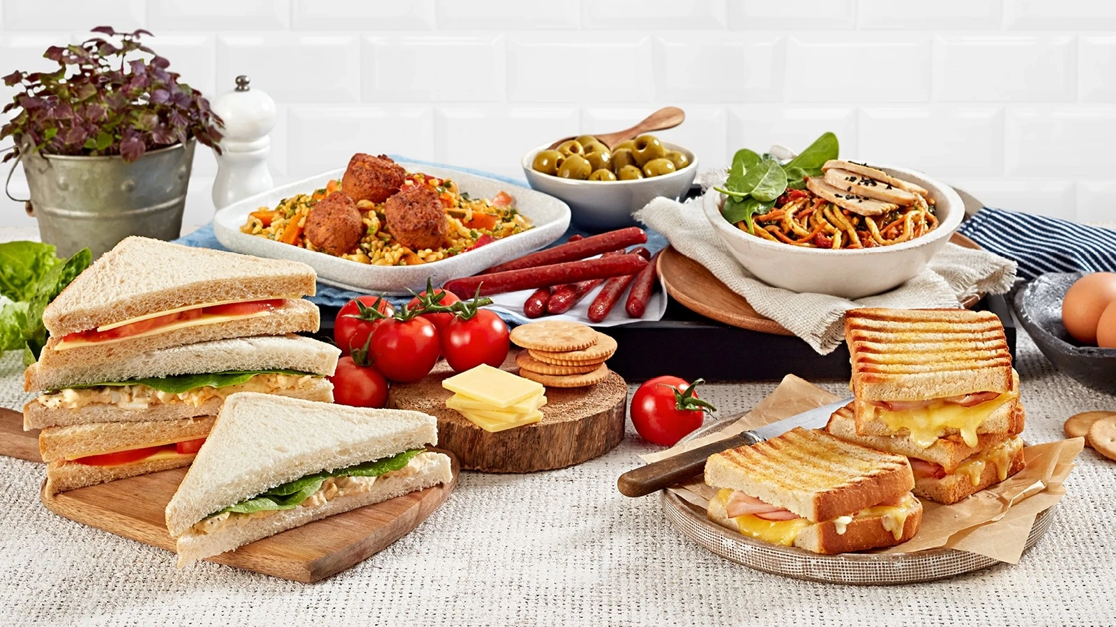 A tasty spread of savoury snacks you might find on a Jetstar flight: ham-and-cheese toasties, salad sandwiches, crackers, olives and noodles.