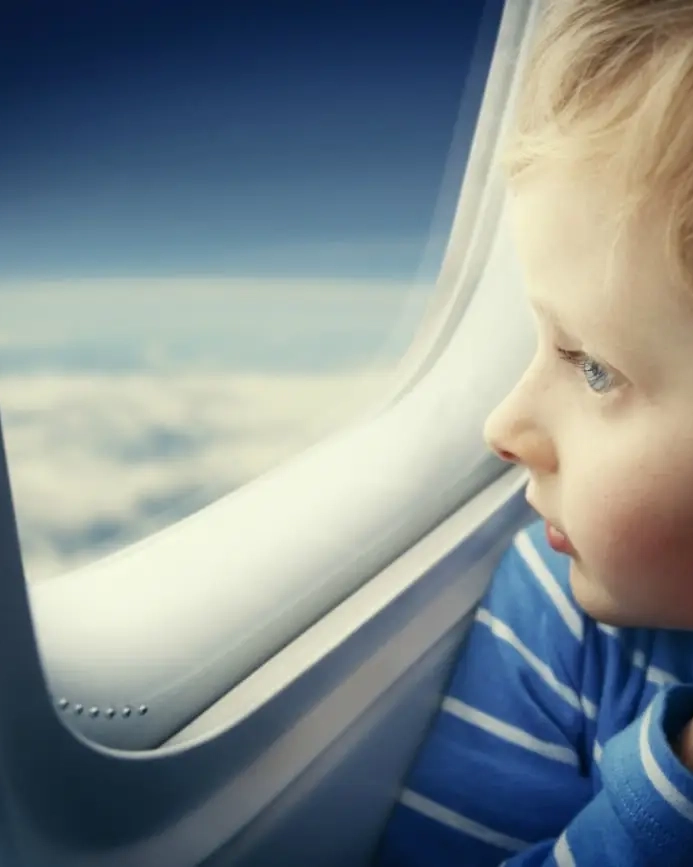 Little girl looking on the outside of the airplane. Image credit: iStock