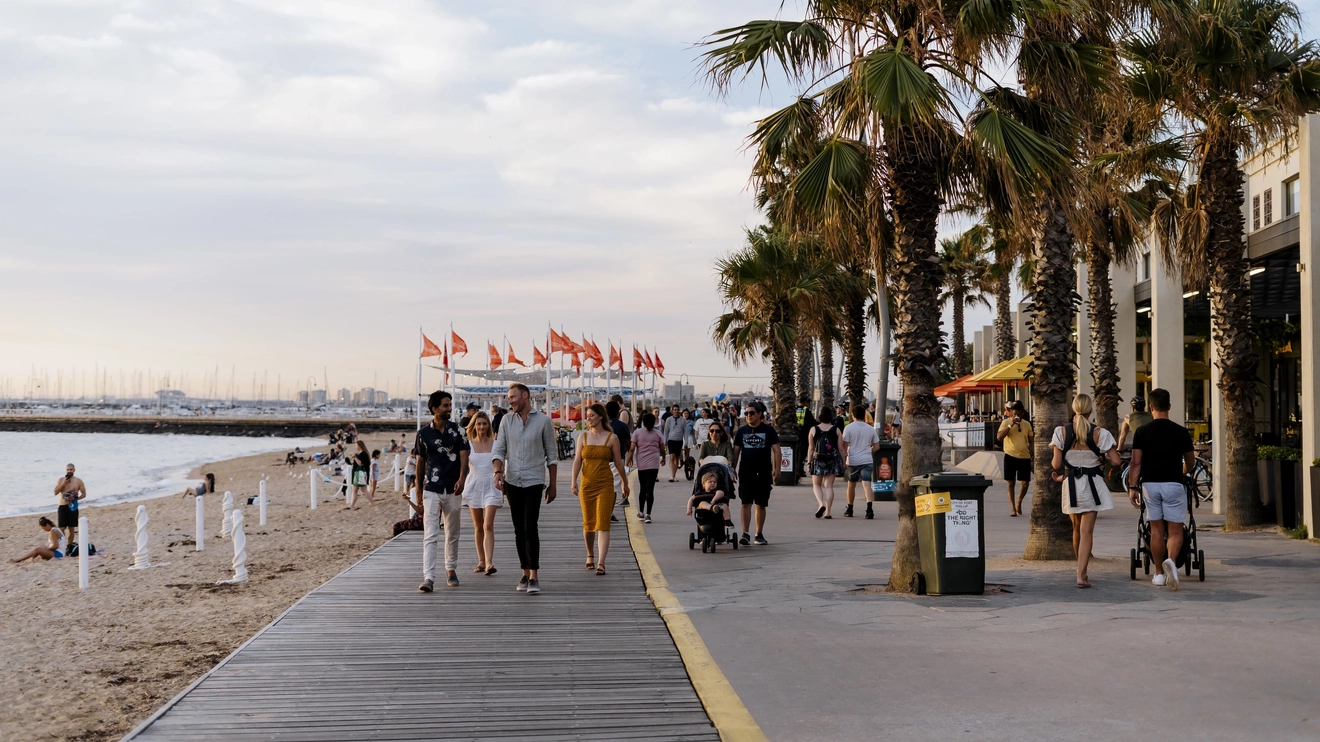 People strolling alongside Melbourne's St Kilda Beach at sunset. Image credit: Visit Victoria