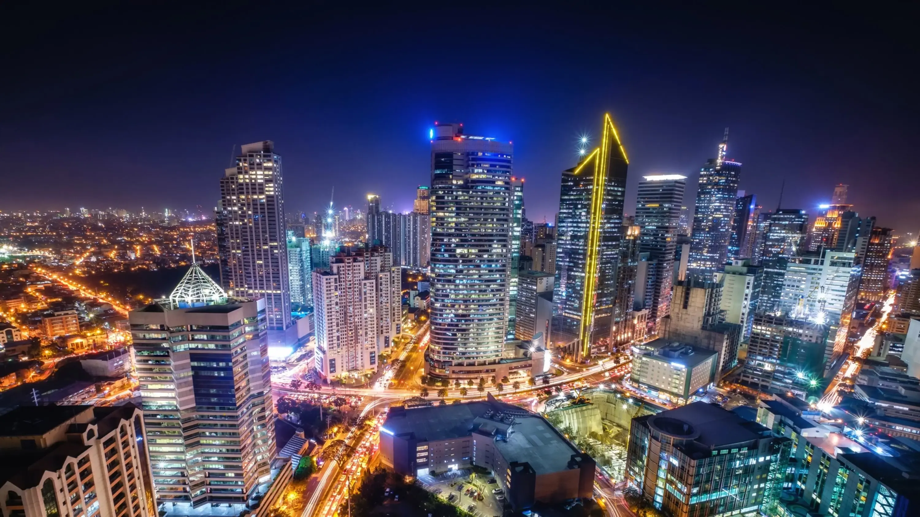 Aerial view of Manila's financial and business district skyline at night, with illuminated skyscrapers and busy roads. Image credit: stock.adobe.com