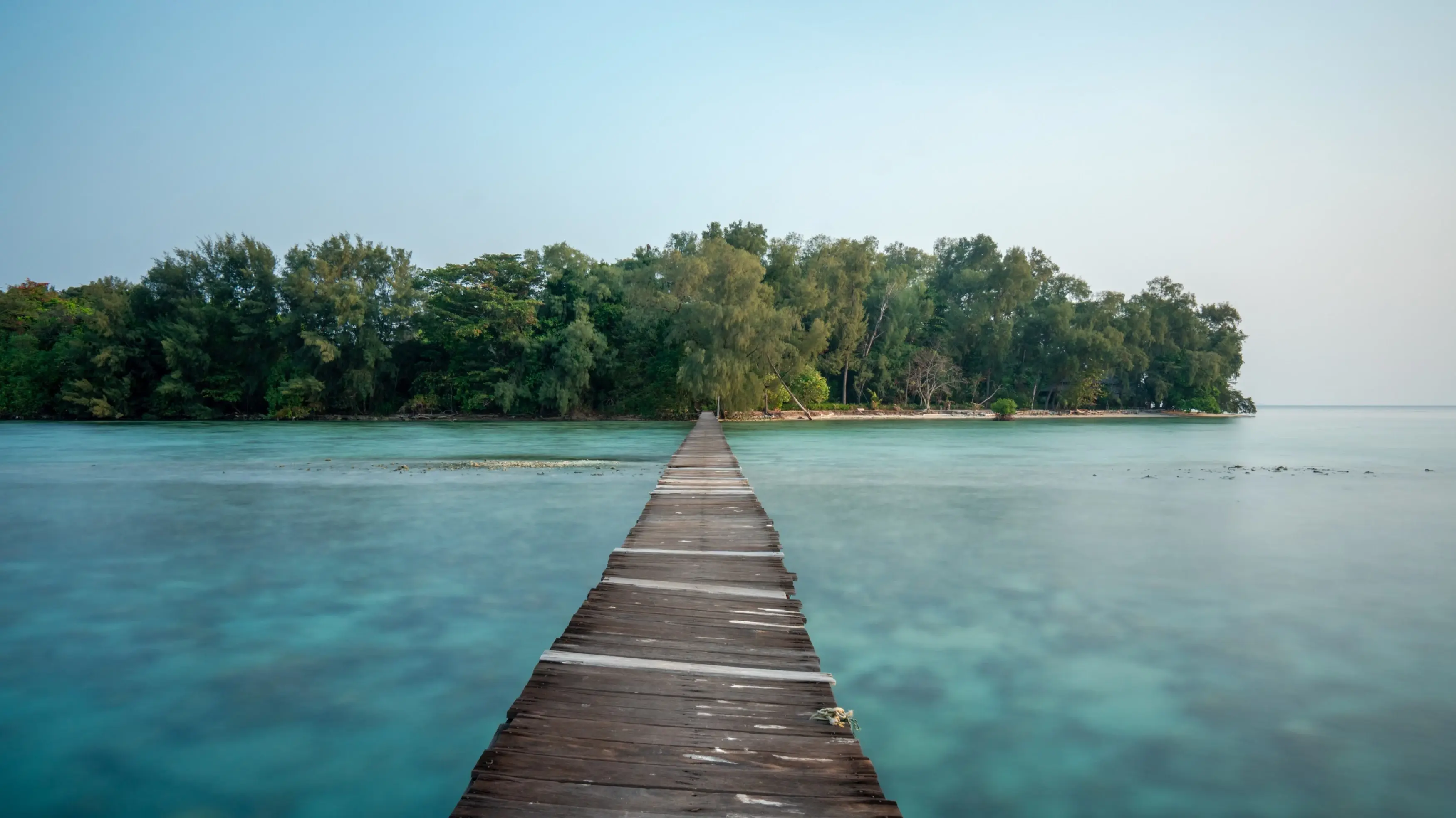 Long, narrow jetty leads over turquoise water to Kotok Island, part of the Thousand Islands, off the coast of Jakarta. Image credit: stock.adobe.com