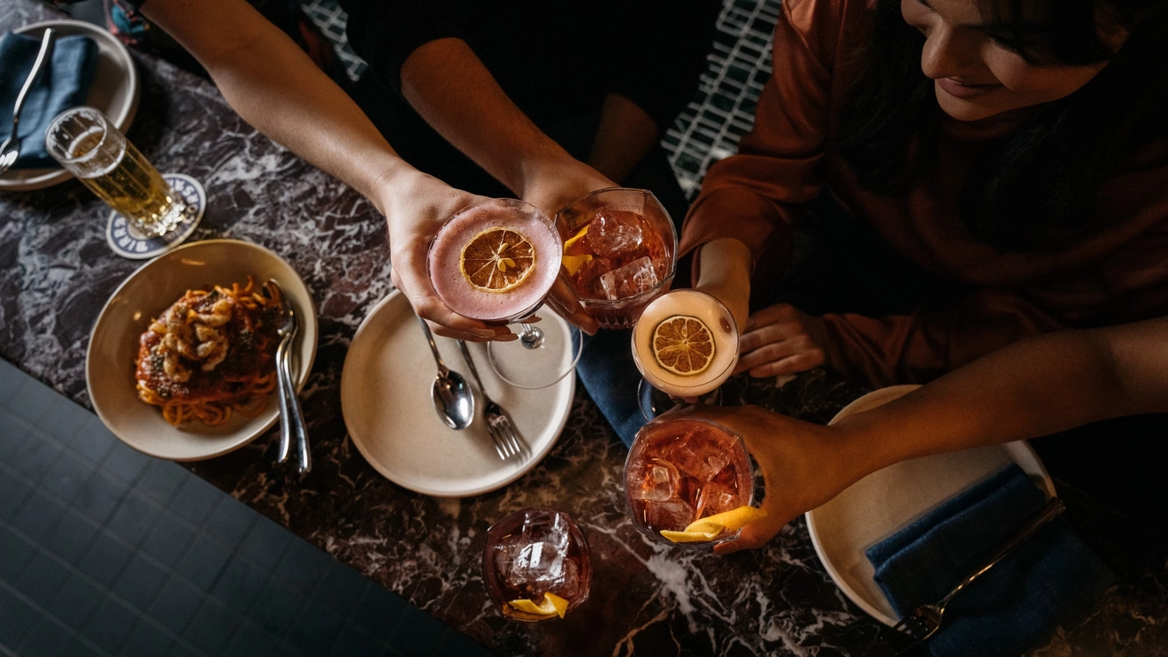  Aerial view of people holding cocktails by drinks and food on the bar at Fugazzi Bar and Dining Room, Adelaide. Image credit: South Australian Tourism Commission