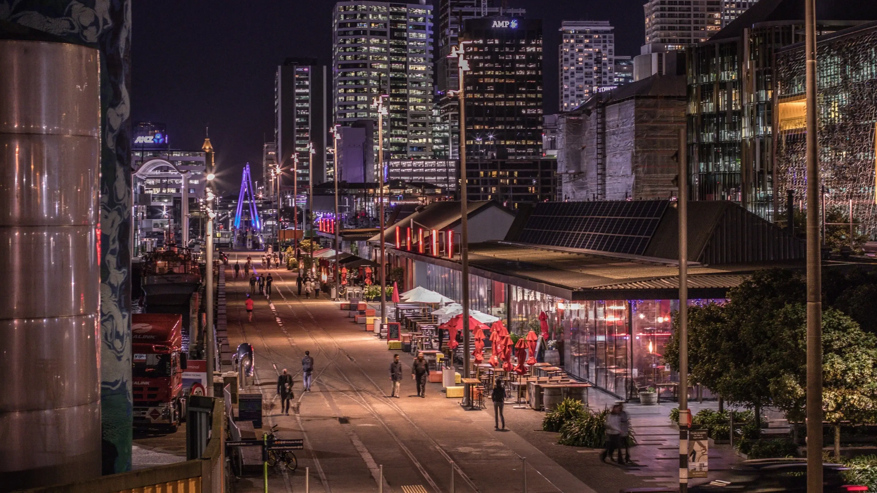 Bars and restaurants in Wynyard Quarter at night with cityscape behind, Auckland, New Zealand.