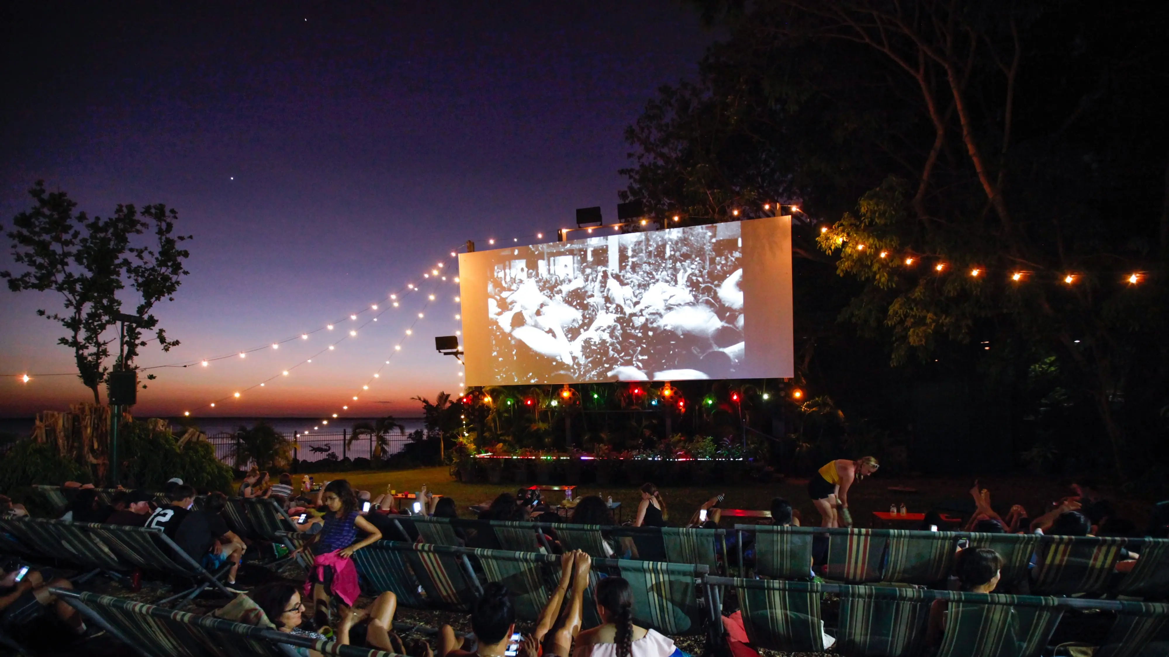 People at an outdoor movie screening at Darwin's Deckchair Cinema at sunset. Image credit: Tourism NT/Friederike Franze