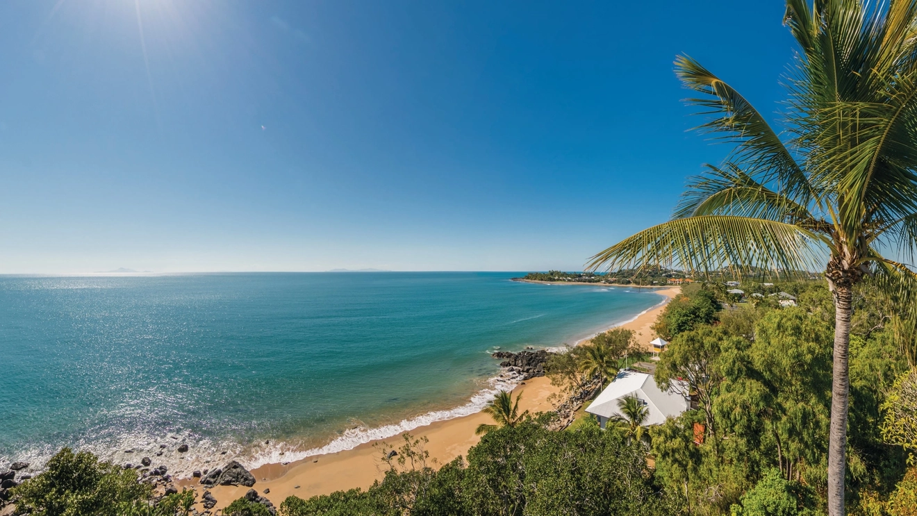 Aerial view of palm trees surrounding sand and water at Eimeo Beach. Image credit: Aaron Spence/Tourism and Events Queensland