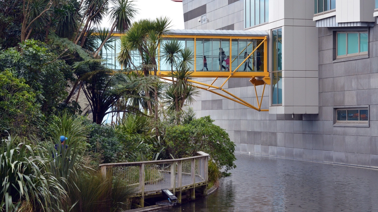The grey brick exterior of the Museum of New Zealand, with a moat and glass walkway, Wellington.