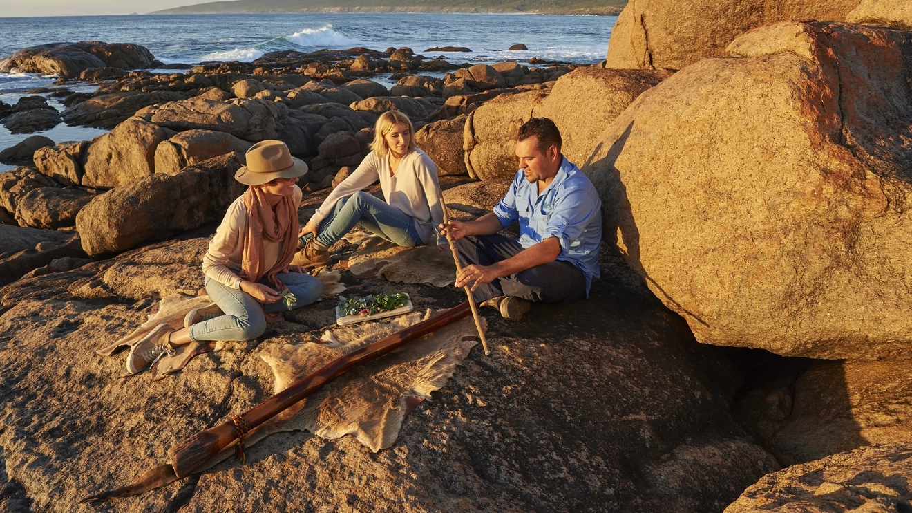 Aboriginal tour guide shows traditional artefacts to two tourists at Cape Naturaliste, Western Australia. Image credit: Frances Andrijich.