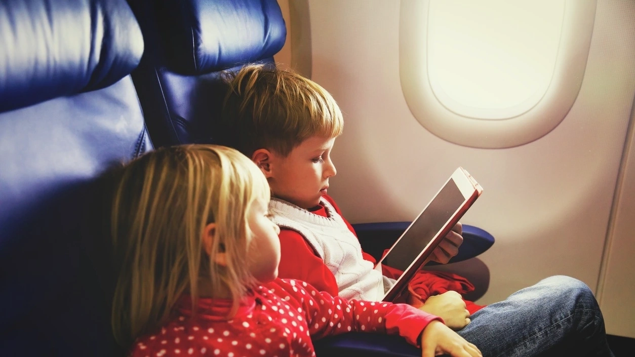 Two kids watching on an IPad in an Airplane. Image credit: iStock