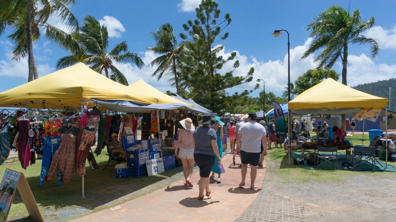 People strolling along the outdoor Airlie Beach market with the beach and palm trees in the background, Whitsunday Coast, Queensland. Image credit: Olga Kashubin/Shutterstock.com