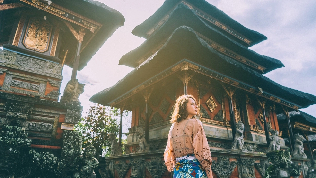 A woman stands outside a temple in Bali.