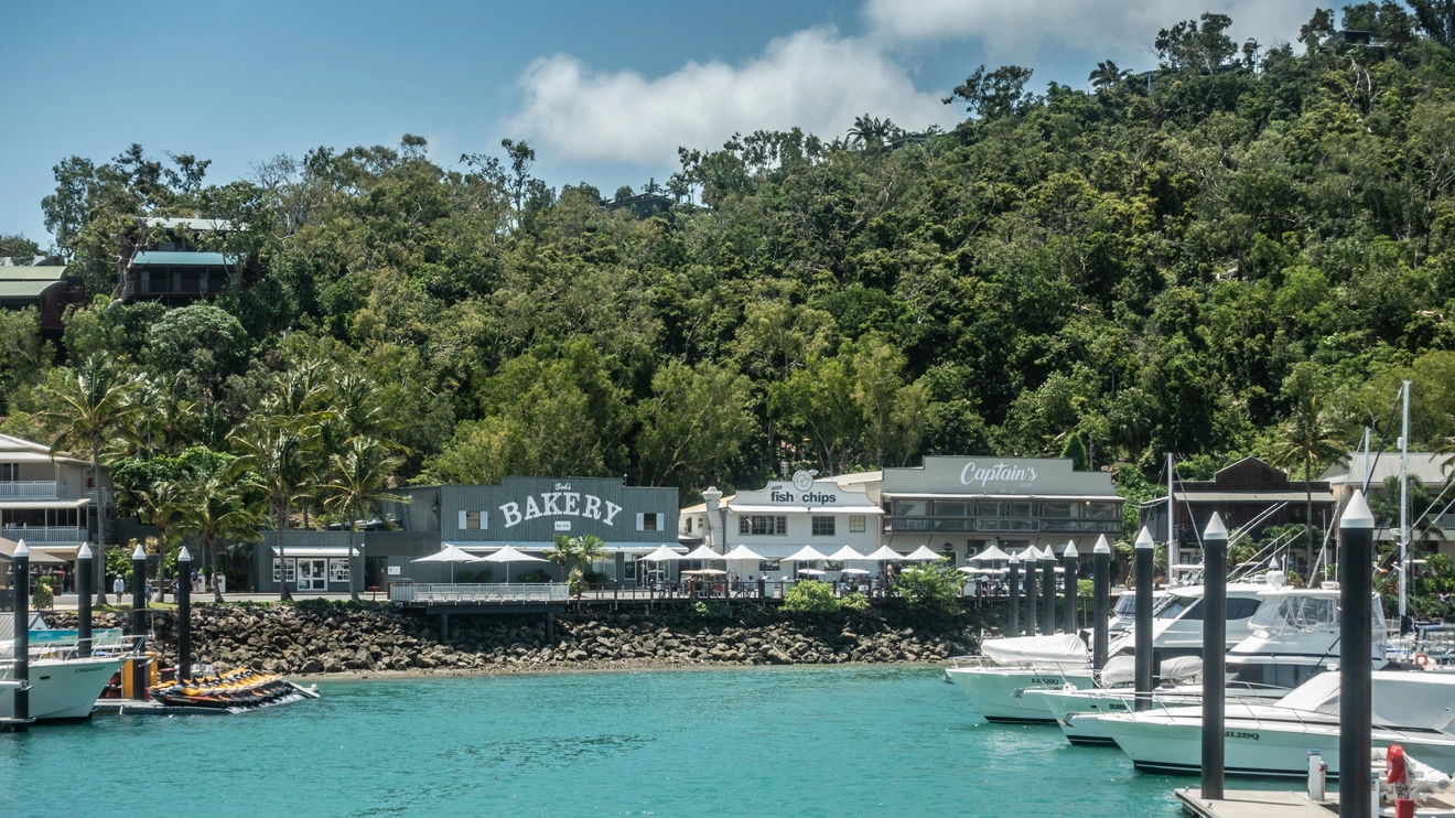 Bakery and other eateries on Front Street, with marina in foreground and forest in the background. Hamilton Island. Image credit: Claudine Van Massenhove/Shutterstock.com