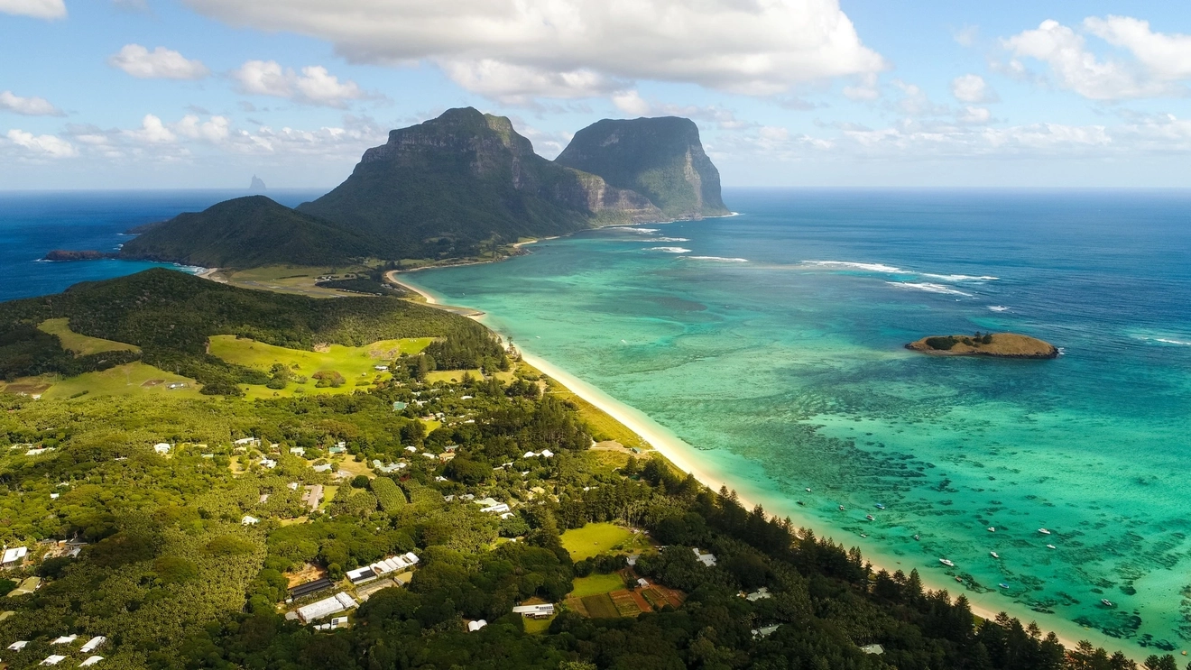 Aerial view of Lord Howe Island with bush, beach, the blue lagoon and Mt Gower in the background.