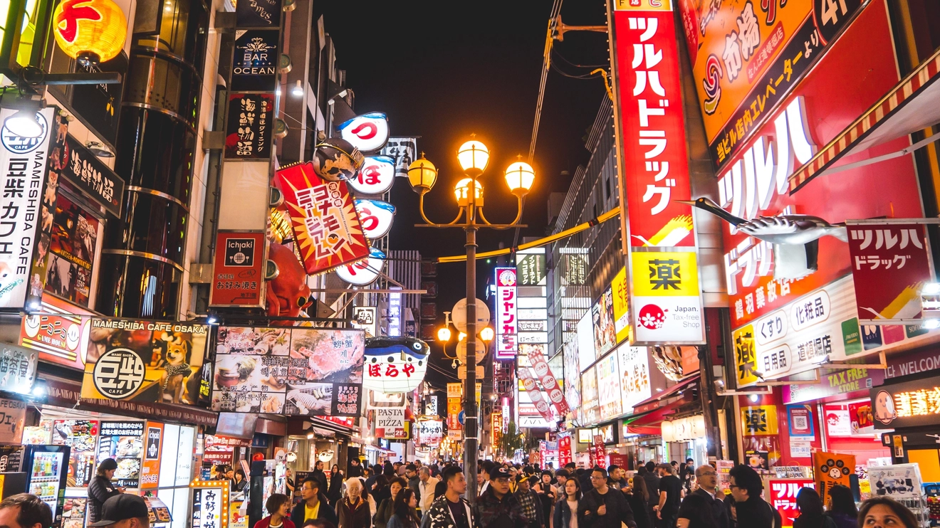 Crowds in neon-lit, busy Dotonburi street at night, Osaka, Japan. Image credit: Nattapol Sritongcom – stock.adobe.com