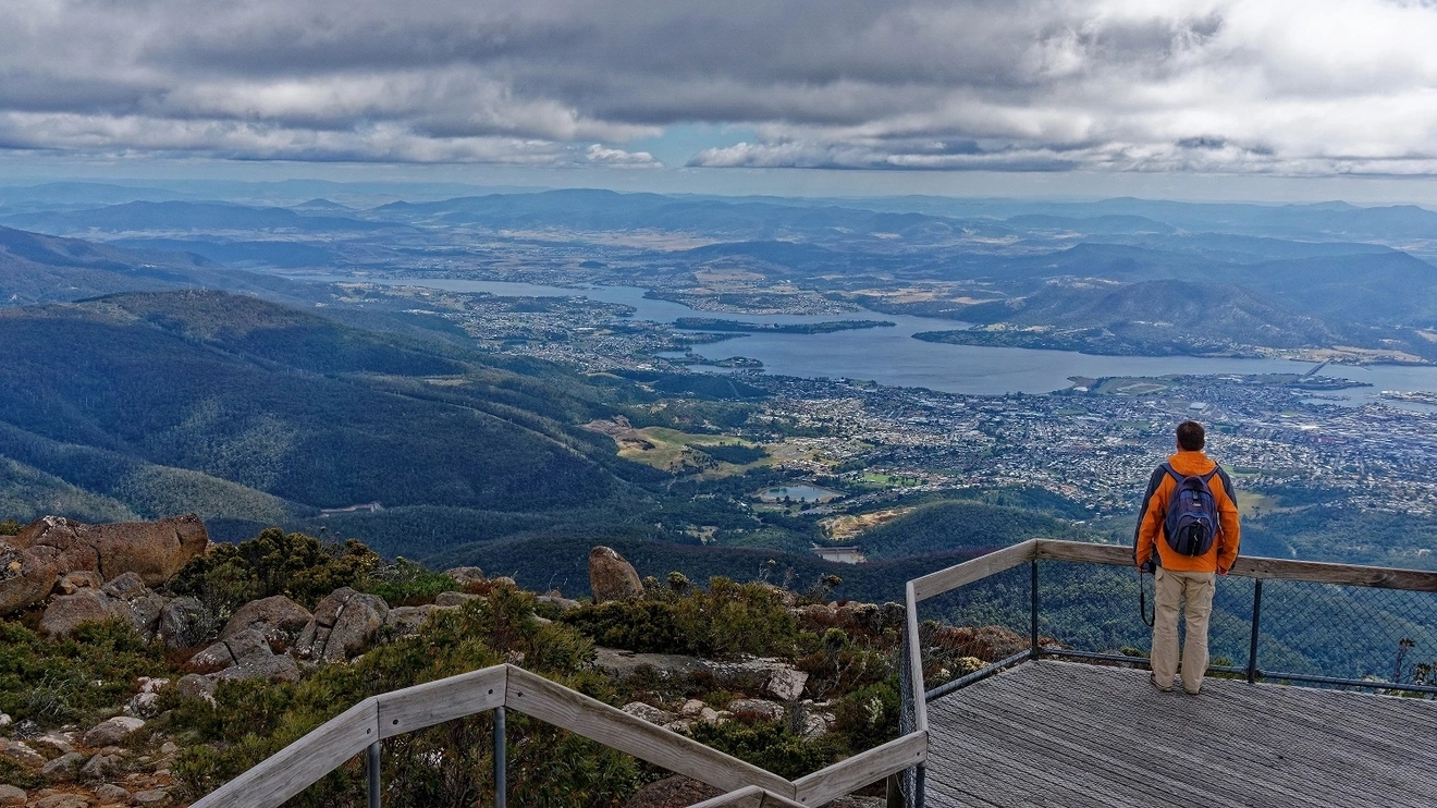 Man wearing backpack admires view of Hobart from the lookout at kunanyi/Mount Wellington. Image credit: stock.adobe.com