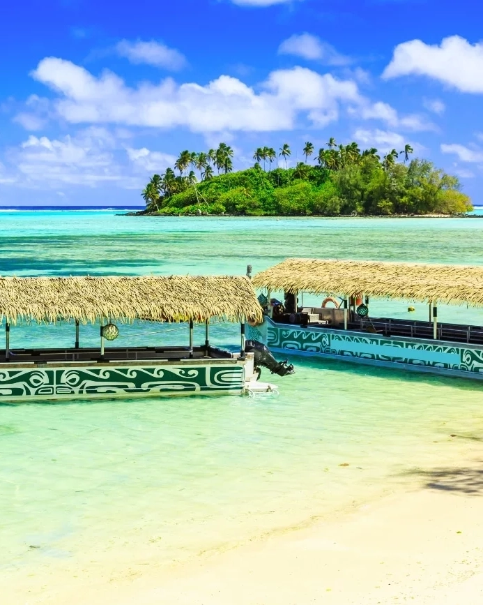 Two flat-bottomed boats on turquoise water with island in background, Rarotonga, Cook Islands. Image credit: stock.adobe.com