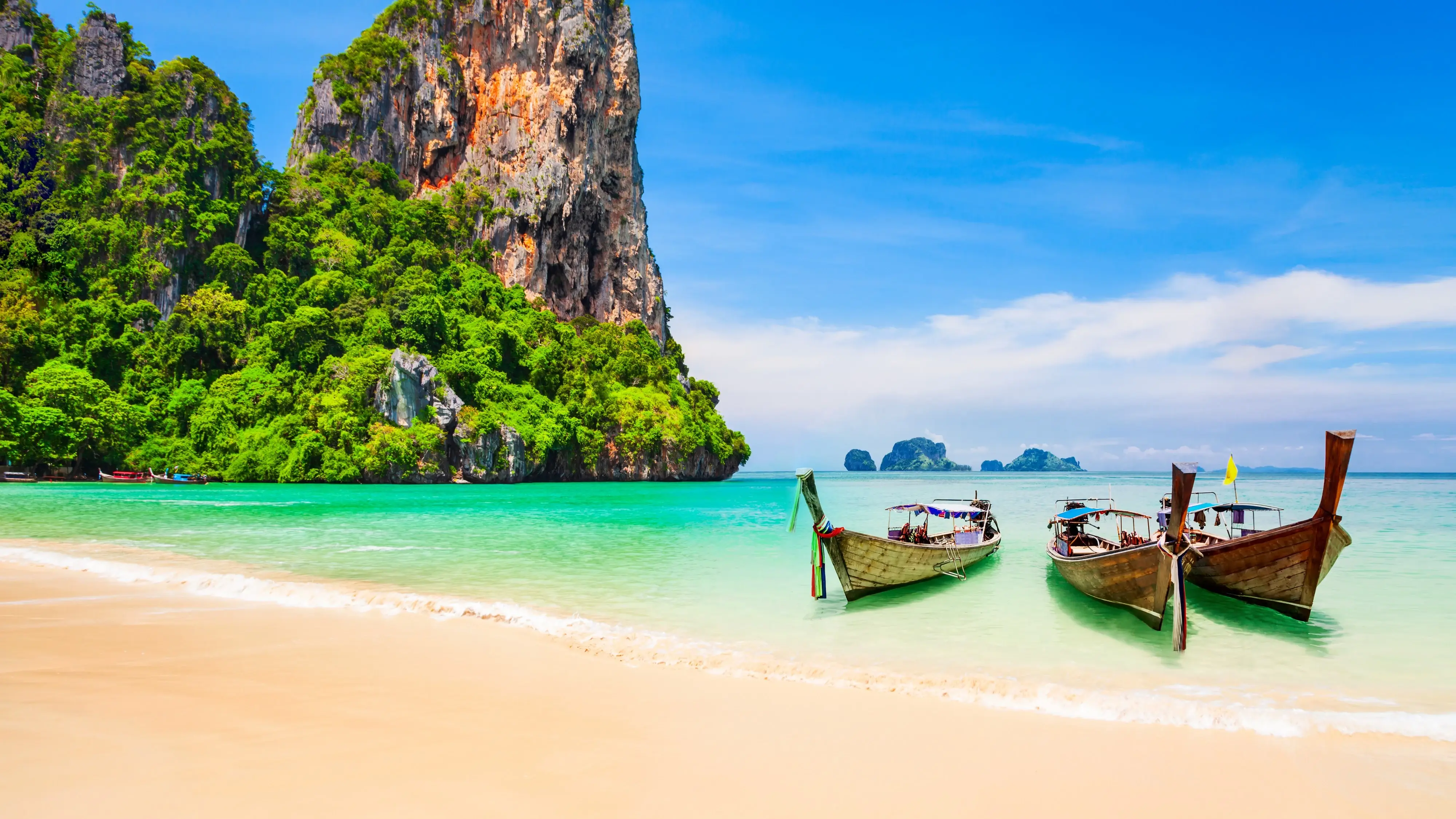 Three longtail boats moored at the beach with limestone outcrop and islands in the background, Thailand. Image credit: stock.adobe.com