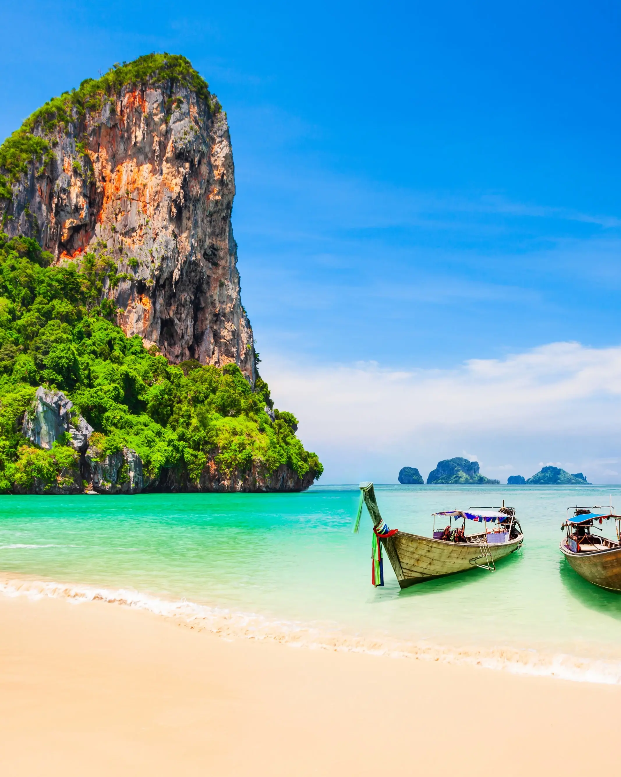 Three longtail boats moored at the beach with limestone outcrop and islands in the background, Thailand. Image credit: stock.adobe.com