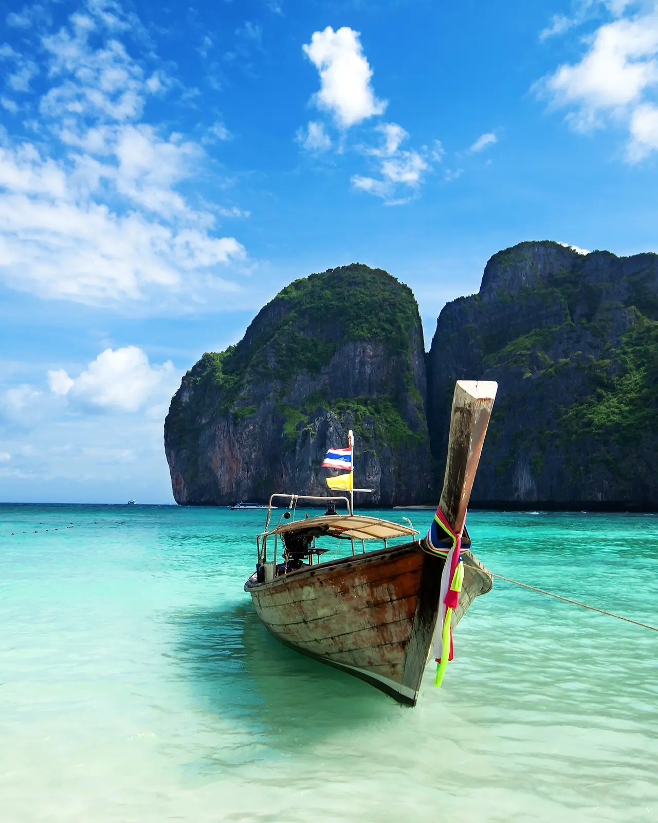 Longtail boat on turquoise water of Maya Bay, Phuket, with limestone islands in the background, on a sunny day. Image credit: Shutterstock