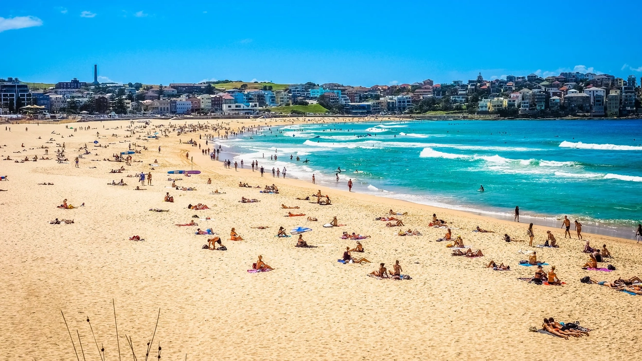 Bondi Beach on a sunny day with people sitting on the sand. Image credit: Shutterstock