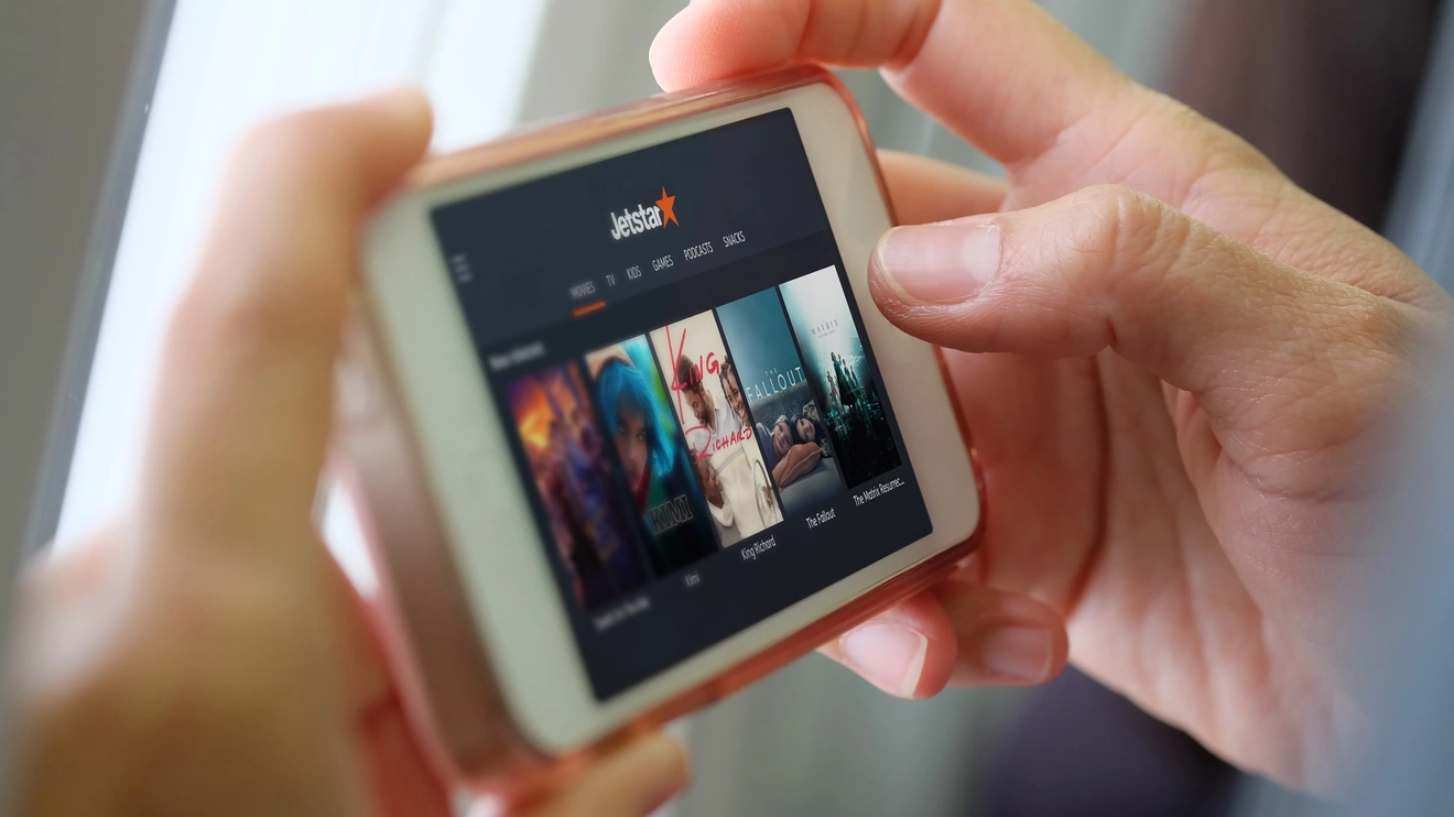 Someone holding a personal mobile device showing the Jetstar Entertainment Plus menu.