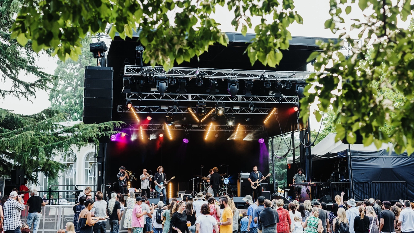 Live music performance on an outdoor stage with people dancing in the foreground at Festivale, held at Launceston's City Park. Image credit: Tourism Tasmania/Adam Gibson