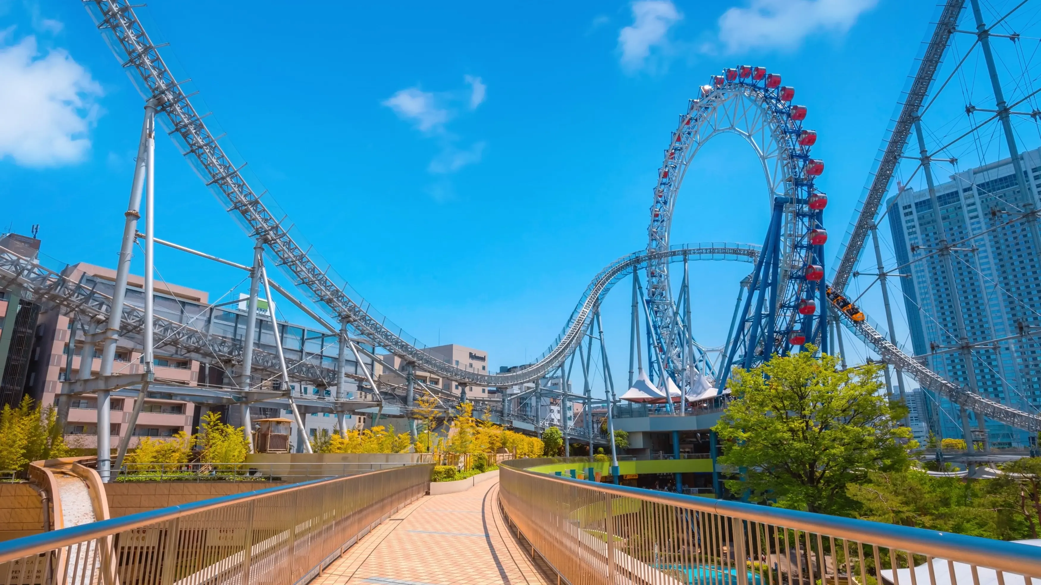 A sunny day with blue sky and rollercoaster tracks running above a pedestrian walkway. Image credit: stock.adobe.com