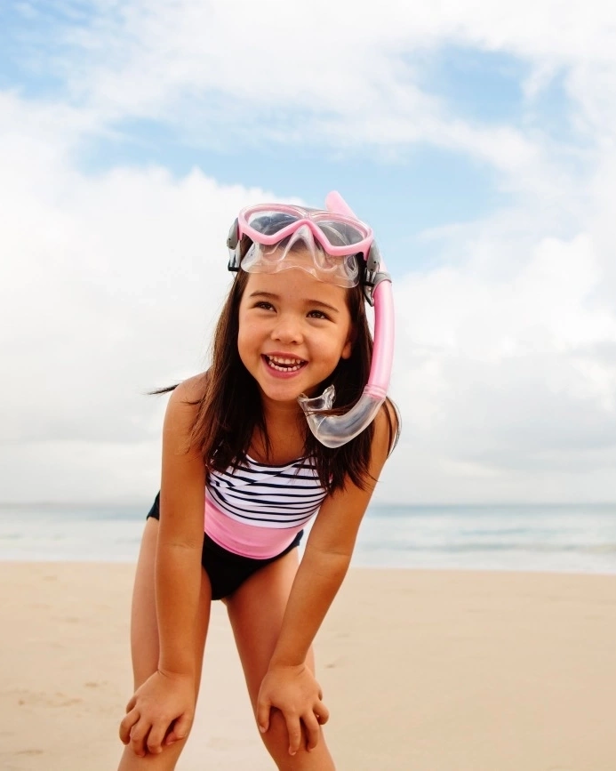Young girl with snorkel standing on the sand at Clarke’s Beach, Byron Bay. Image credit: Destination NSW