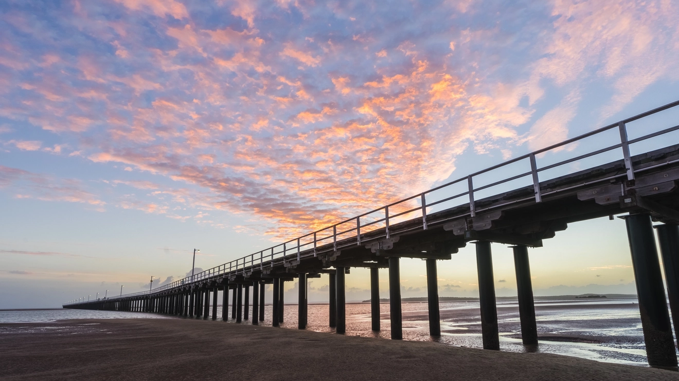 Silhouetted view of Urangan Pier and the beach at sunrise in Hervey Bay. Image credit: Shutterstock