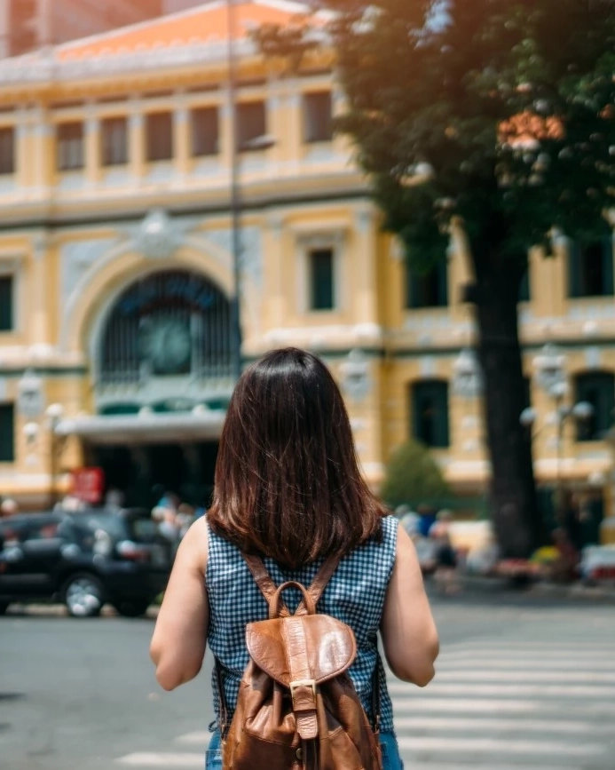 Young woman wearing a backpack admires Ho Chi Minh City’s Central Post Office. Image credit: stock.adobe.com