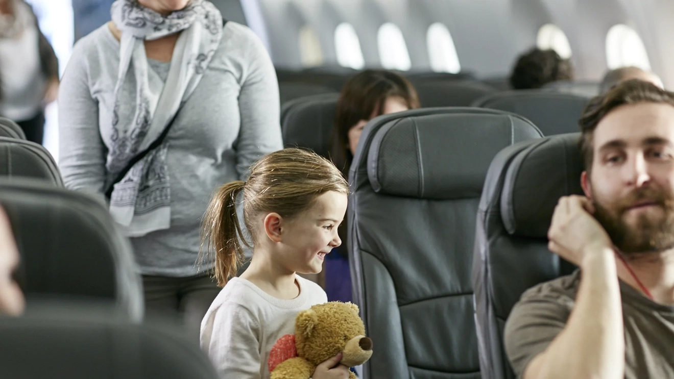 Happy kid going to her seat on airplane.