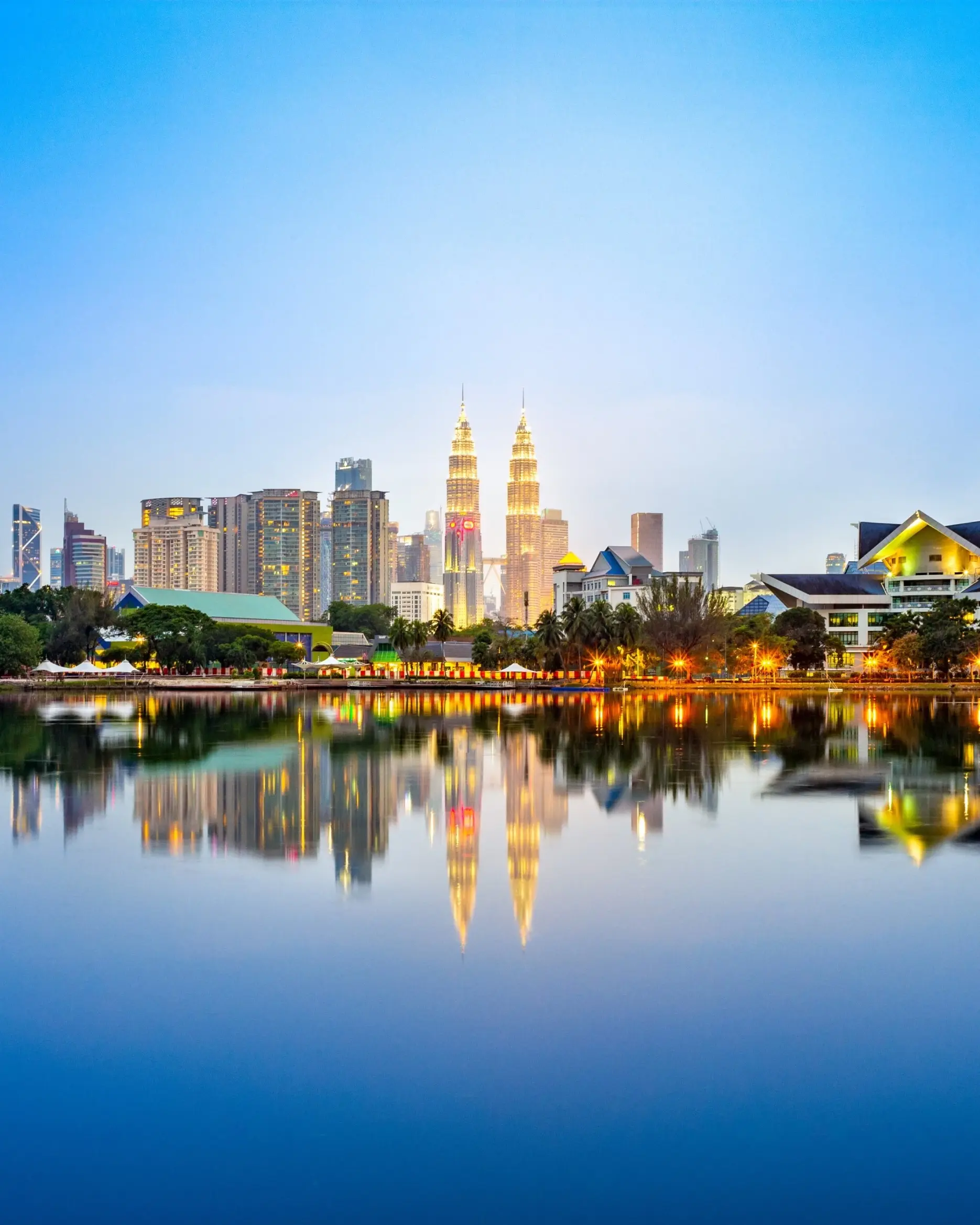 Kuala Lumpur's city skyline at night, with lights reflecting on the lake in the foreground. Image credit: stock.adobe.com